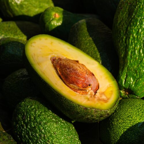Close-up of a ripe avocado halved to reveal its seed and green flesh, emphasizing freshness and health.