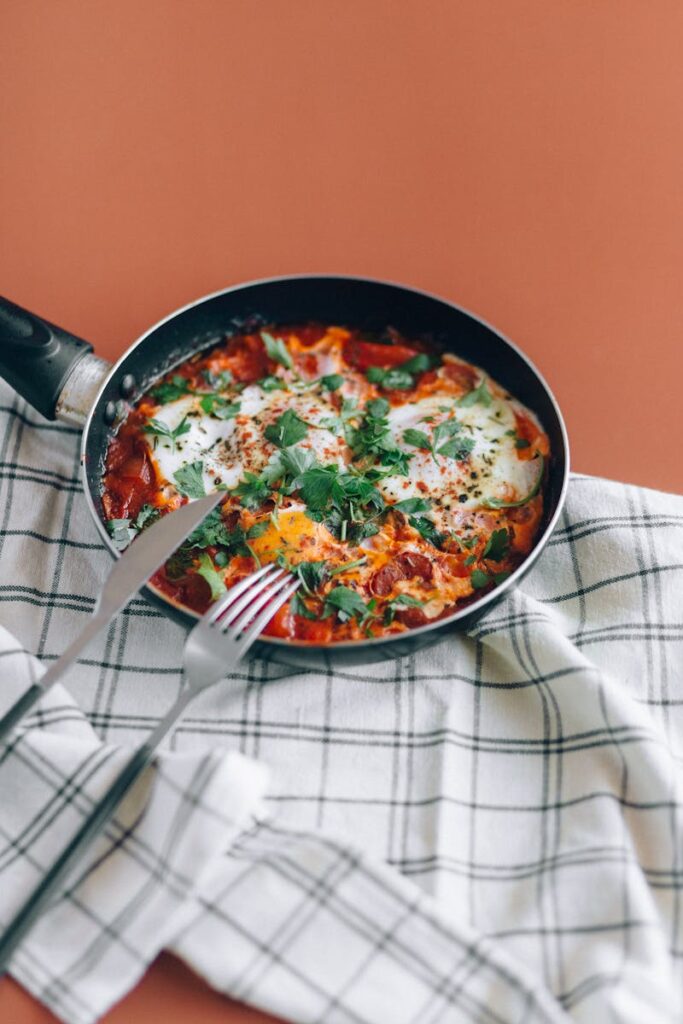Fresh shakshuka in a skillet with herbs on a table. Perfect for brunch.