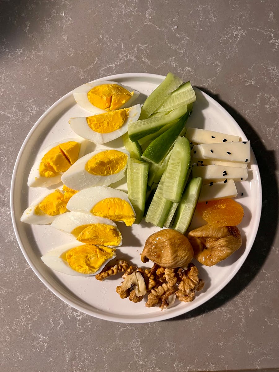 Colorful platter with boiled eggs, cucumbers, cheese, nuts, and dried fruits.