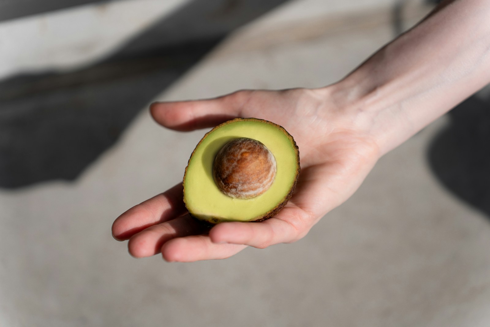 a person holding an avocado in their hand